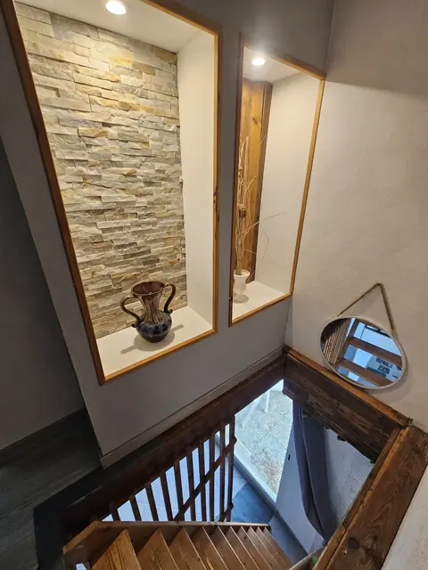 Les niches éclairées et l'escalier en bois vers les chambres