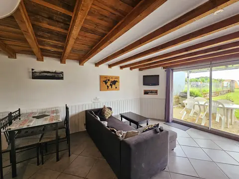 Le salon de L'Escale, poutres apparentes et baie vitrée sur la terrasse