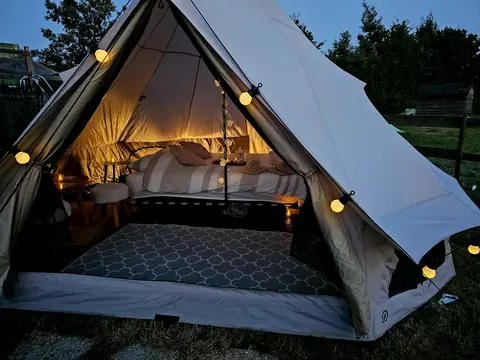 L'Astro-Tipi ouvert à la tombée de la nuit, lit et bougies